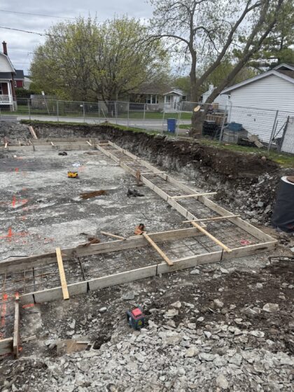 Coffrages de semelles de fondation avec armature installés dans une excavation sur un terrain résidentiel