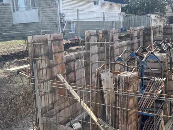 Rangée de coffrages de murs de fondation avec armature horizontale sur un chantier résidentiel ensoleillé