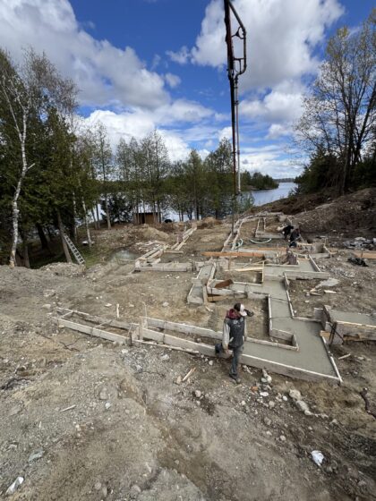 Flèche d'une pompe à béton déployée au-dessus des semelles coffrées d'un chantier riverain