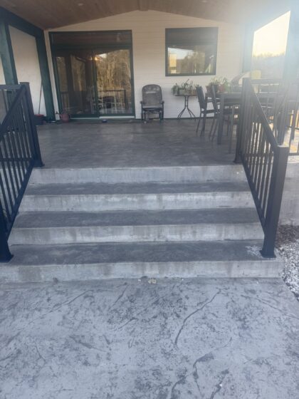 Escalier de béton menant à une galerie en béton estampé gris avec garde-corps d'aluminium noir