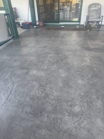 Surface de galerie couverte finie en béton estampé gris texturé devant une porte-patio