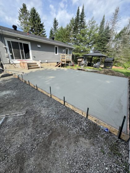 Grande dalle de béton fraîchement coulée et finie dans la cour arrière d'une résidence