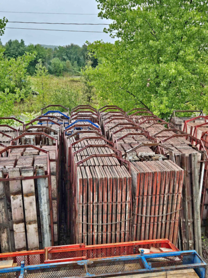 Rangées de panneaux de coffrage à béton empilés sur des supports métalliques dans une cour d'entreposage